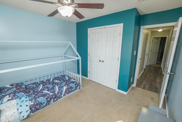 carpeted bedroom with ceiling fan, a closet, and a textured ceiling