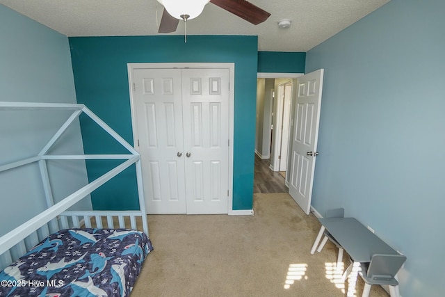 bedroom with ceiling fan, a closet, a textured ceiling, and carpet