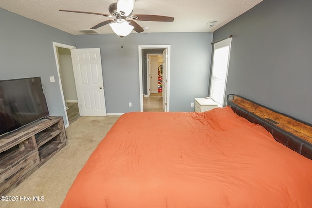 bedroom featuring a textured ceiling, light colored carpet, and ceiling fan