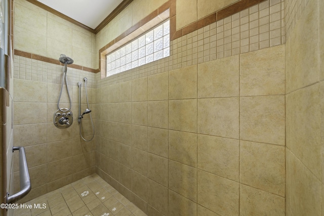 bathroom with a tile shower and ornamental molding