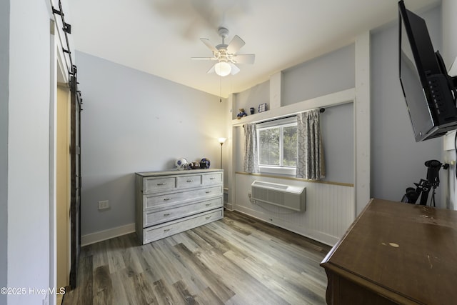 bedroom with hardwood / wood-style floors, a wall mounted AC, and ceiling fan