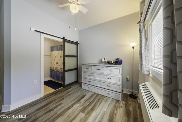 bedroom featuring dark wood-type flooring, ceiling fan, and a barn door