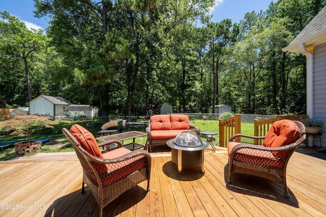 wooden deck featuring an outdoor living space with a fire pit and a storage shed