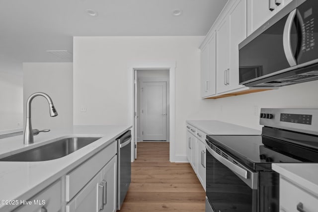 kitchen featuring white cabinetry, appliances with stainless steel finishes, sink, and light wood-type flooring