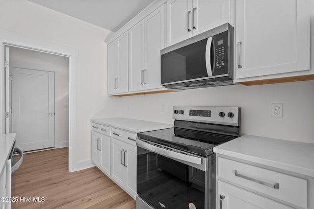 kitchen with stainless steel appliances, light hardwood / wood-style floors, and white cabinets