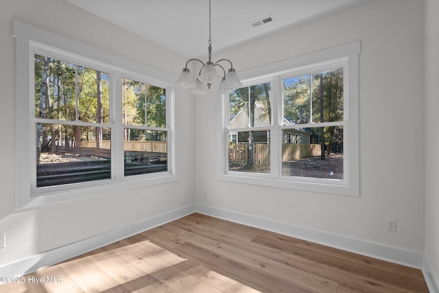 unfurnished dining area with hardwood / wood-style floors and a chandelier