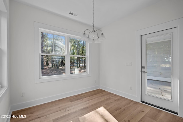 unfurnished dining area featuring light hardwood / wood-style flooring and a notable chandelier