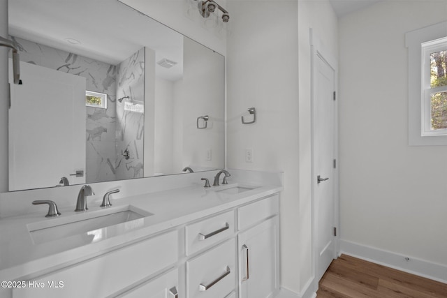 bathroom with vanity, a healthy amount of sunlight, hardwood / wood-style floors, and tiled shower