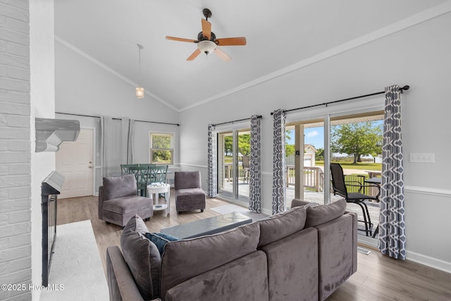 living area featuring ceiling fan, wood finished floors, high vaulted ceiling, baseboards, and a fireplace
