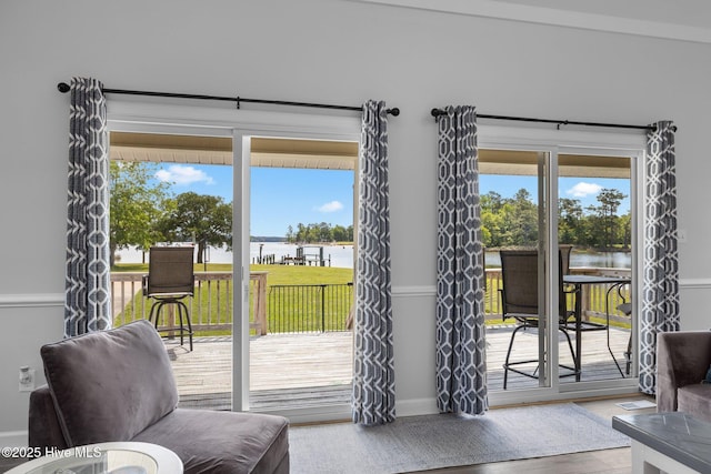 doorway with a water view, healthy amount of natural light, and baseboards