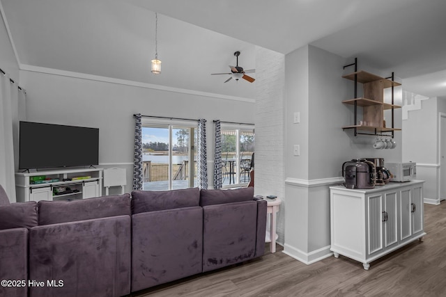 living room featuring ornamental molding, wood finished floors, a ceiling fan, and baseboards