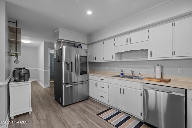 kitchen with appliances with stainless steel finishes, light wood-type flooring, a sink, and white cabinets