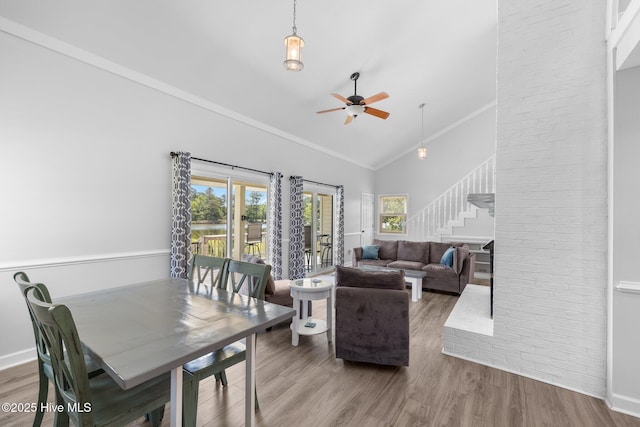 living area with stairway, healthy amount of natural light, ceiling fan, wood finished floors, and ornamental molding