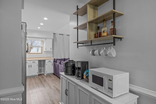 bar featuring white microwave, light wood finished floors, and recessed lighting