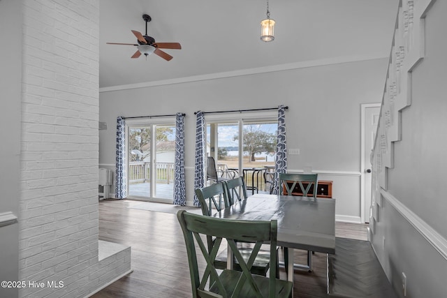 dining room with lofted ceiling, ornamental molding, a wainscoted wall, and dark wood finished floors