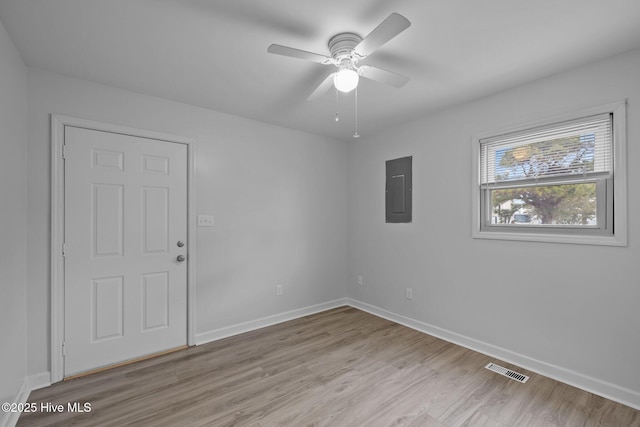 unfurnished room with visible vents, light wood-style floors, ceiling fan, electric panel, and baseboards