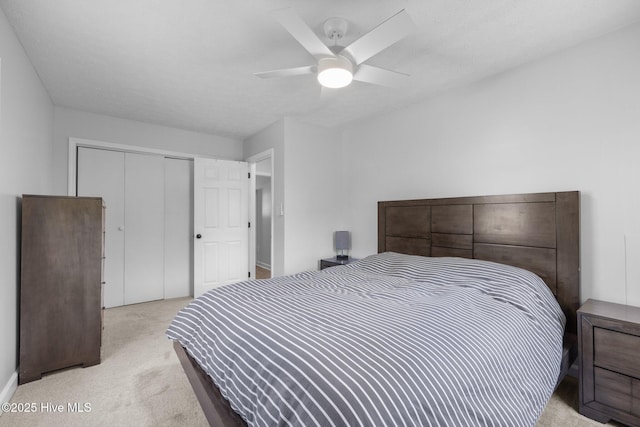 bedroom featuring light colored carpet, a closet, and a ceiling fan