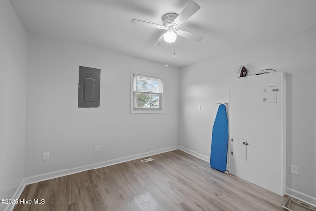 spare room featuring wood finished floors, electric panel, and baseboards