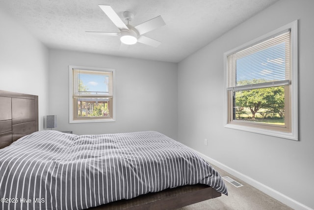 carpeted bedroom with baseboards, a ceiling fan, and a textured ceiling