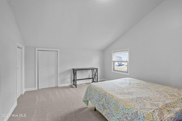 carpeted bedroom featuring lofted ceiling, a textured ceiling, and baseboards