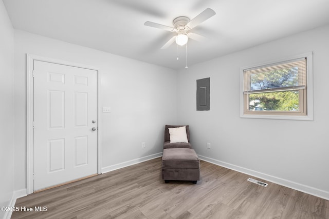 unfurnished room with electric panel, light wood-style flooring, baseboards, and ceiling fan