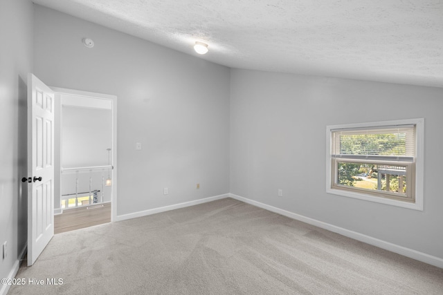 unfurnished bedroom featuring a textured ceiling, carpet, baseboards, and vaulted ceiling