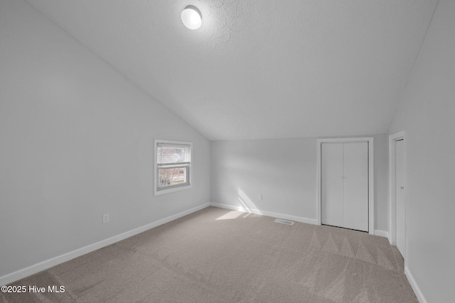 bonus room with baseboards, visible vents, vaulted ceiling, and carpet flooring