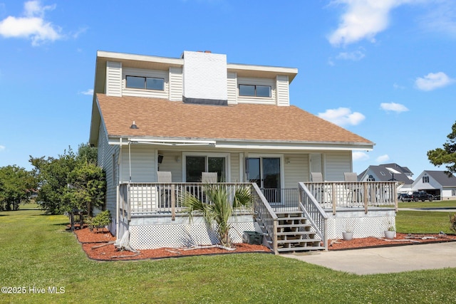 view of front of home with a porch, a shingled roof, a front yard, and a chimney