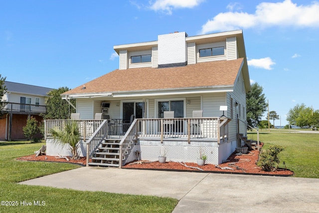 view of front of property with a porch, a chimney, a front yard, and a shingled roof