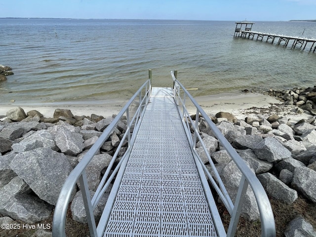 view of dock with a water view and a beach view