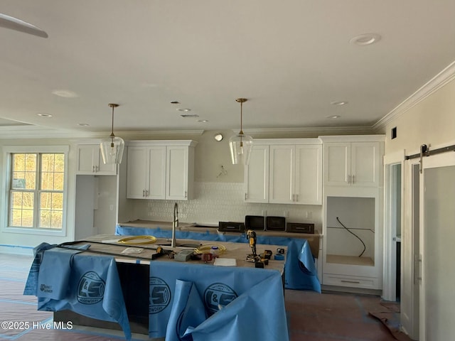 kitchen featuring crown molding, decorative light fixtures, a barn door, decorative backsplash, and white cabinets