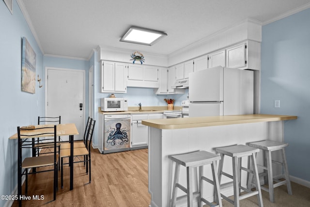 kitchen with sink, ornamental molding, kitchen peninsula, white appliances, and white cabinets