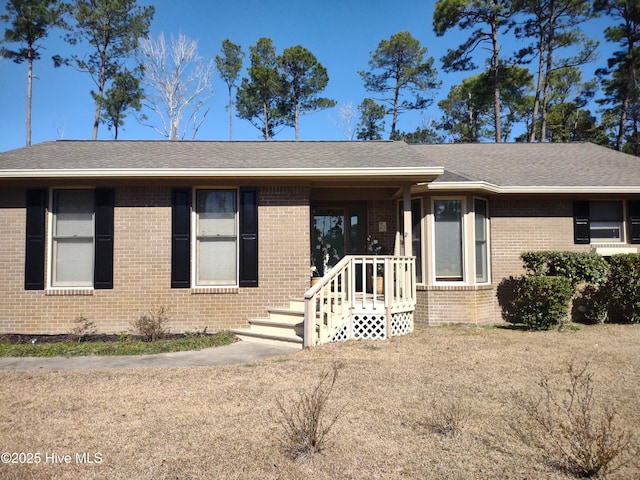 ranch-style house featuring a shingled roof and brick siding