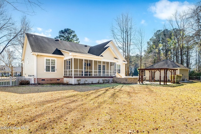 rear view of house featuring a gazebo, a lawn, and a sunroom