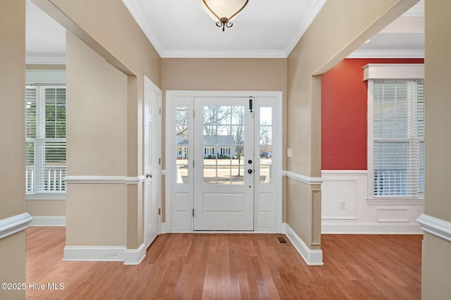 entrance foyer with ornamental molding and light hardwood / wood-style floors