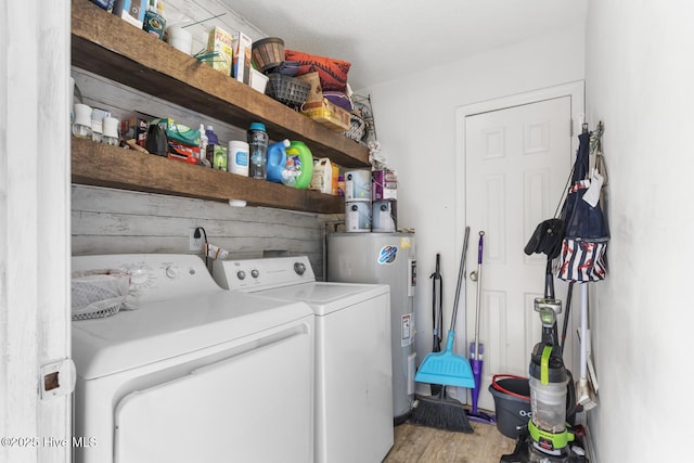 clothes washing area with water heater, hardwood / wood-style flooring, and independent washer and dryer