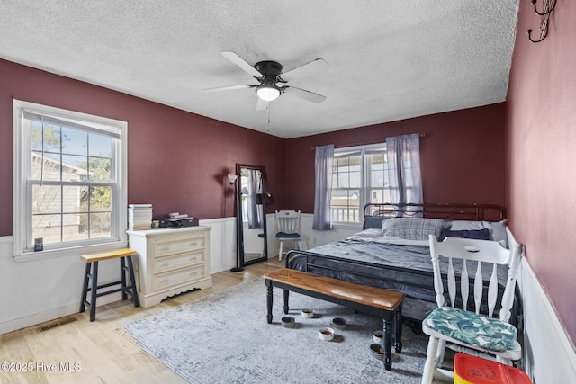 bedroom with ceiling fan, light hardwood / wood-style flooring, and a textured ceiling