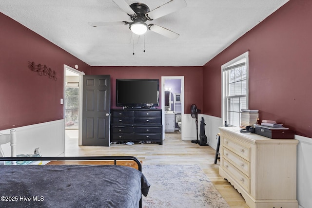 bedroom featuring connected bathroom, a textured ceiling, and light wood-type flooring