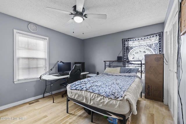 bedroom with ceiling fan, a textured ceiling, and light hardwood / wood-style floors