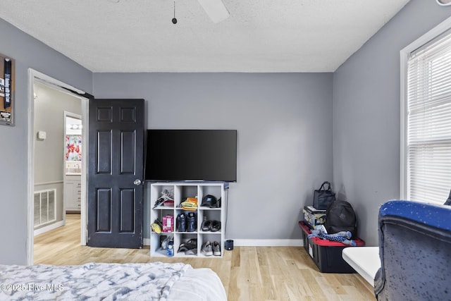 bedroom with a textured ceiling, light hardwood / wood-style floors, and ceiling fan