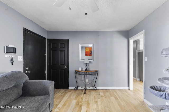 foyer entrance featuring a textured ceiling, ceiling fan, and light wood-type flooring