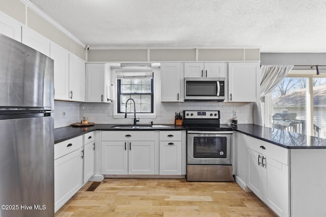 kitchen with backsplash, stainless steel appliances, light hardwood / wood-style flooring, and white cabinets