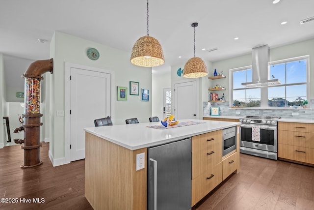 kitchen featuring appliances with stainless steel finishes, island exhaust hood, tasteful backsplash, a kitchen island, and light brown cabinets