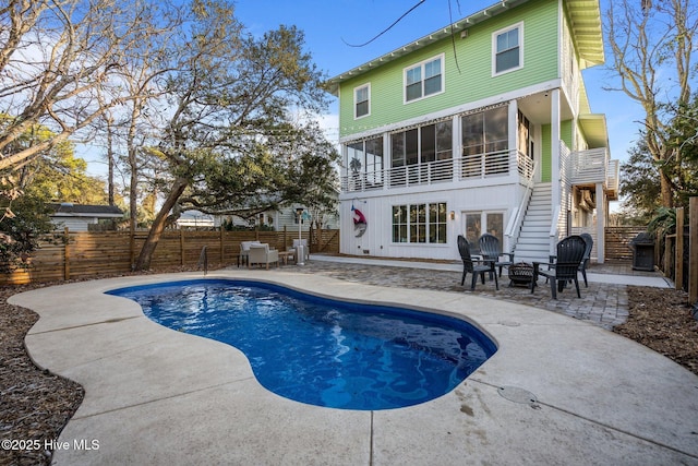 rear view of house featuring a fenced in pool, a patio, and a balcony