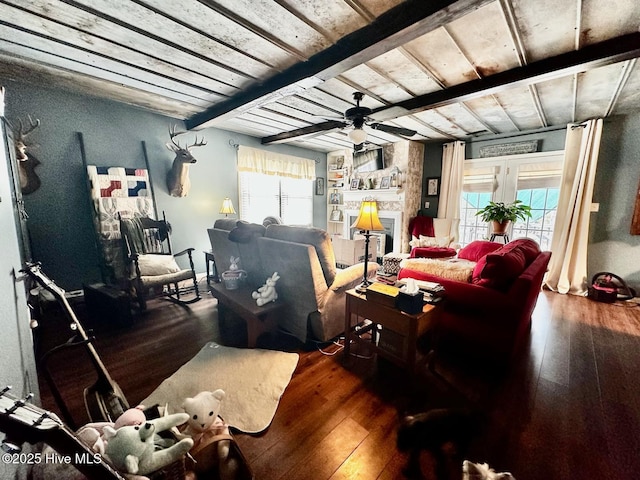 living room featuring plenty of natural light, dark hardwood / wood-style floors, a large fireplace, and beam ceiling