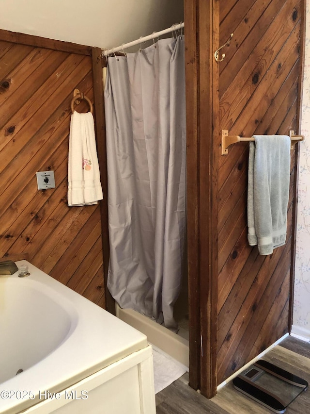 full bath featuring wood walls, a shower with shower curtain, and a sink