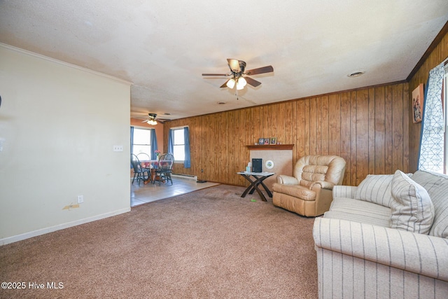 unfurnished living room with crown molding, ceiling fan, carpet flooring, and wood walls