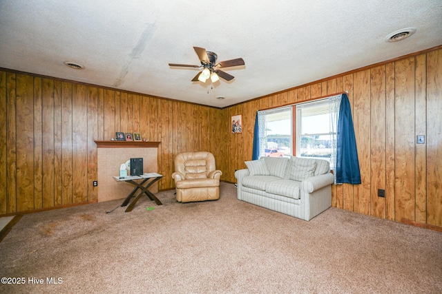 unfurnished living room with ceiling fan, wooden walls, carpet floors, and a textured ceiling