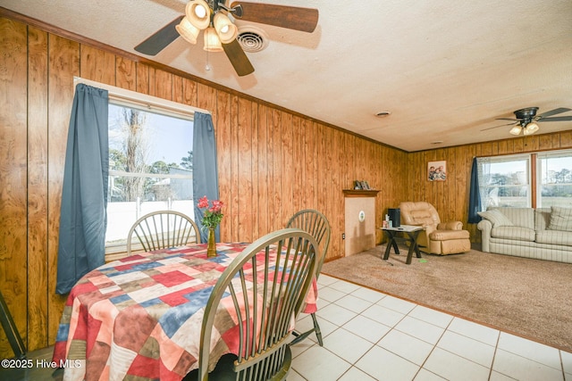 dining space featuring ornamental molding, light carpet, a textured ceiling, and wooden walls