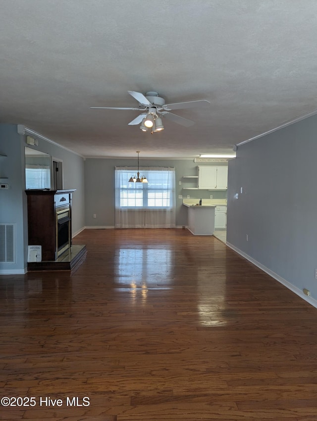 unfurnished living room featuring crown molding, ceiling fan with notable chandelier, a textured ceiling, and dark hardwood / wood-style flooring